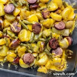Hearty Sausage, Potato, and Green Bean Bake 6 Casserole dish containing sliced sausage, potatoes, green beans, and melted cheese.