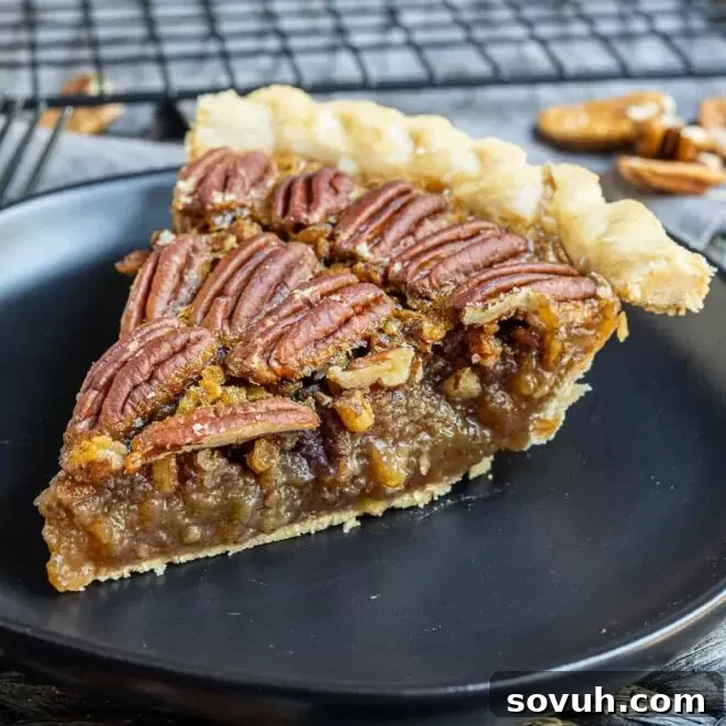 A perfectly sliced piece of Southern Pecan Pie on a black plate, showcasing its rich, golden filling and pecan topping.