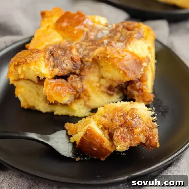 A serving of Pecan Pie Bread Pudding on a black plate with a black fork, showcasing its comforting texture.