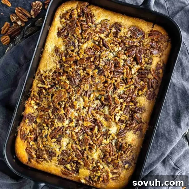 A rectangular baking dish filled with baked pecan cobbler, topped with a golden crust and chopped pecans.