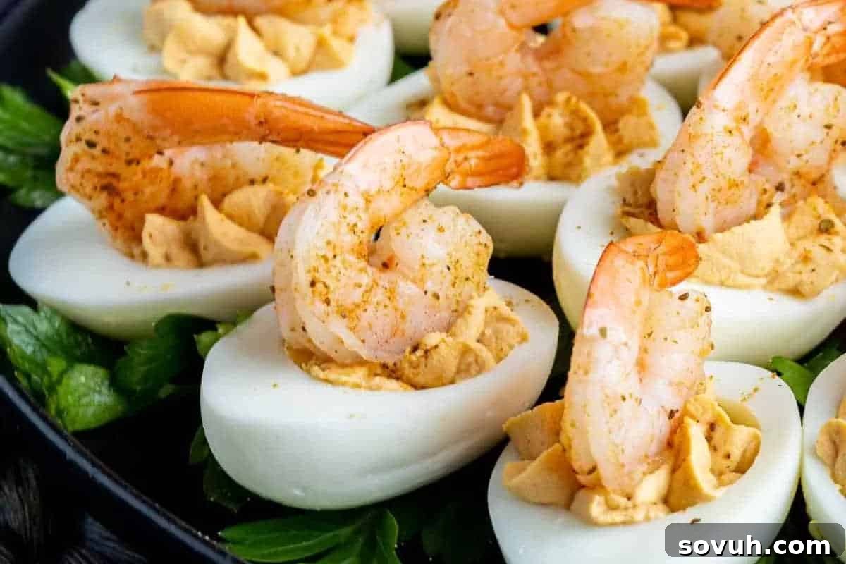 Deviled eggs topped with cooked shrimp on a bed of greens.