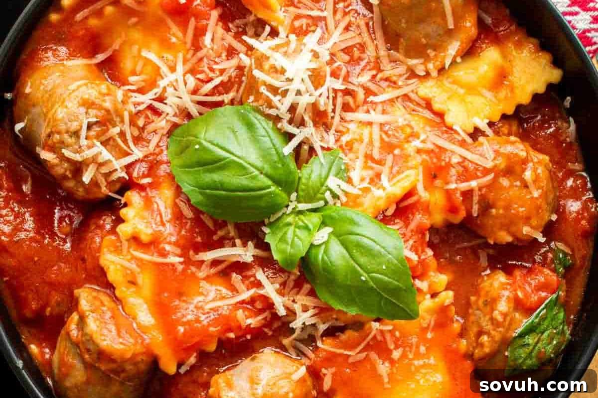 A delightful bowl of ravioli bathed in a rich tomato sauce, generously accompanied by savory meatballs, and beautifully topped with freshly grated parmesan cheese and vibrant green basil leaves.