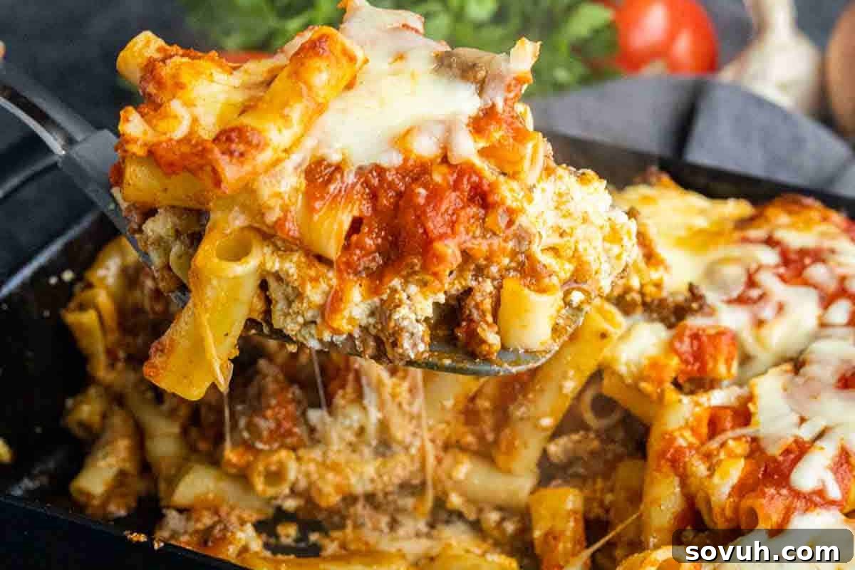 A delectable serving of baked ziti, generously coated with rich tomato sauce and bubbling melted cheese, being carefully lifted from a glass baking dish.