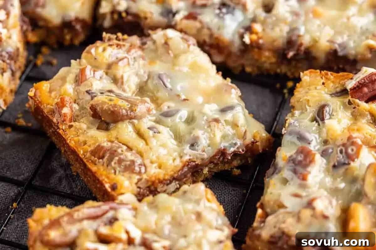 A close-up of rich pecan dessert bars featuring a glossy, inviting nutty topping and a perfectly golden brown crust, meticulously arranged on a sleek black wire cooling rack.