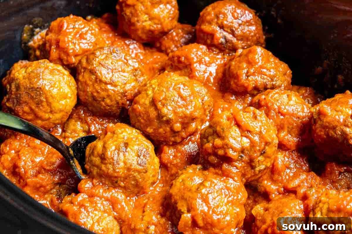 A close-up shot of a deep pan brimming with succulent meatballs bathed in a vibrant red tomato sauce. A serving spoon rests invitingly to the left, ready to dish out this comforting meal.