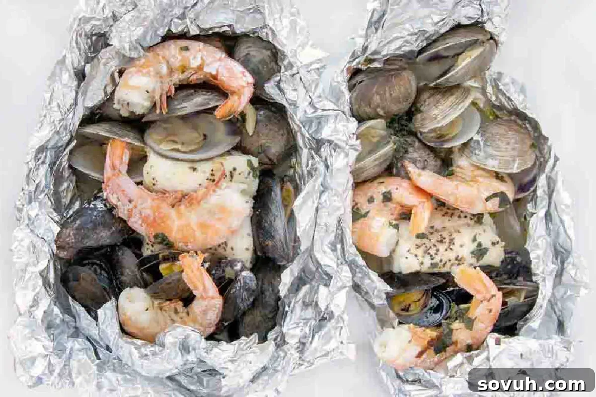 Grilled seafood including shrimp, clams, and fish fillets, wrapped in aluminum foil.