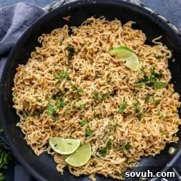 A pan filled with peanut ramen noodles garnished with chopped herbs and two lime wedges on top—an easy ramen recipe perfect for quick, flavorful meals.