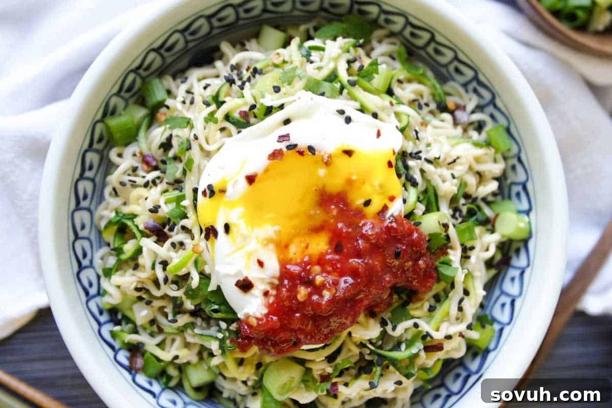 A delightful bowl of noodles, elegantly topped with a soft-cooked egg, a swirl of vibrant chili sauce, a scattering of chopped green onions, and a sprinkle of sesame seeds.