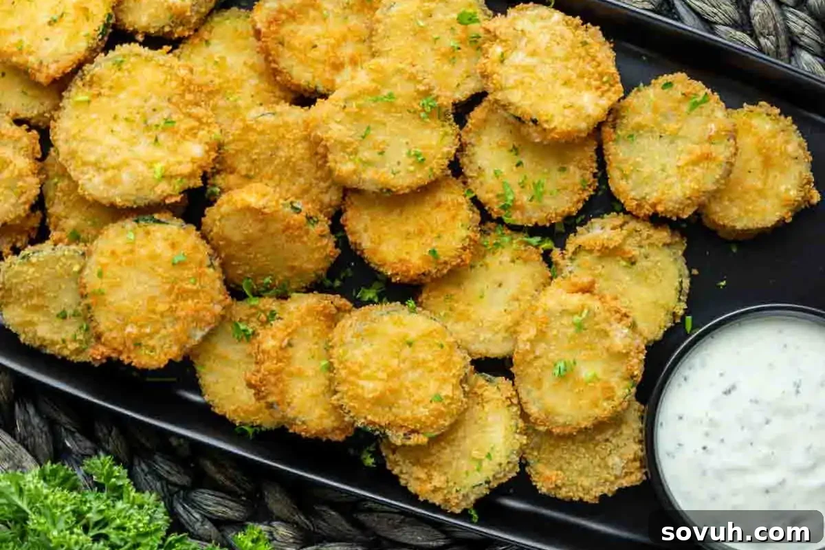 A rustic plate of golden-brown, perfectly breaded fried zucchini fritters, boasting an irresistible crispness, arranged next to a small bowl of creamy, tangy dipping sauce—inspired by creative zucchini recipes and showcasing a delicious appetizer or side.