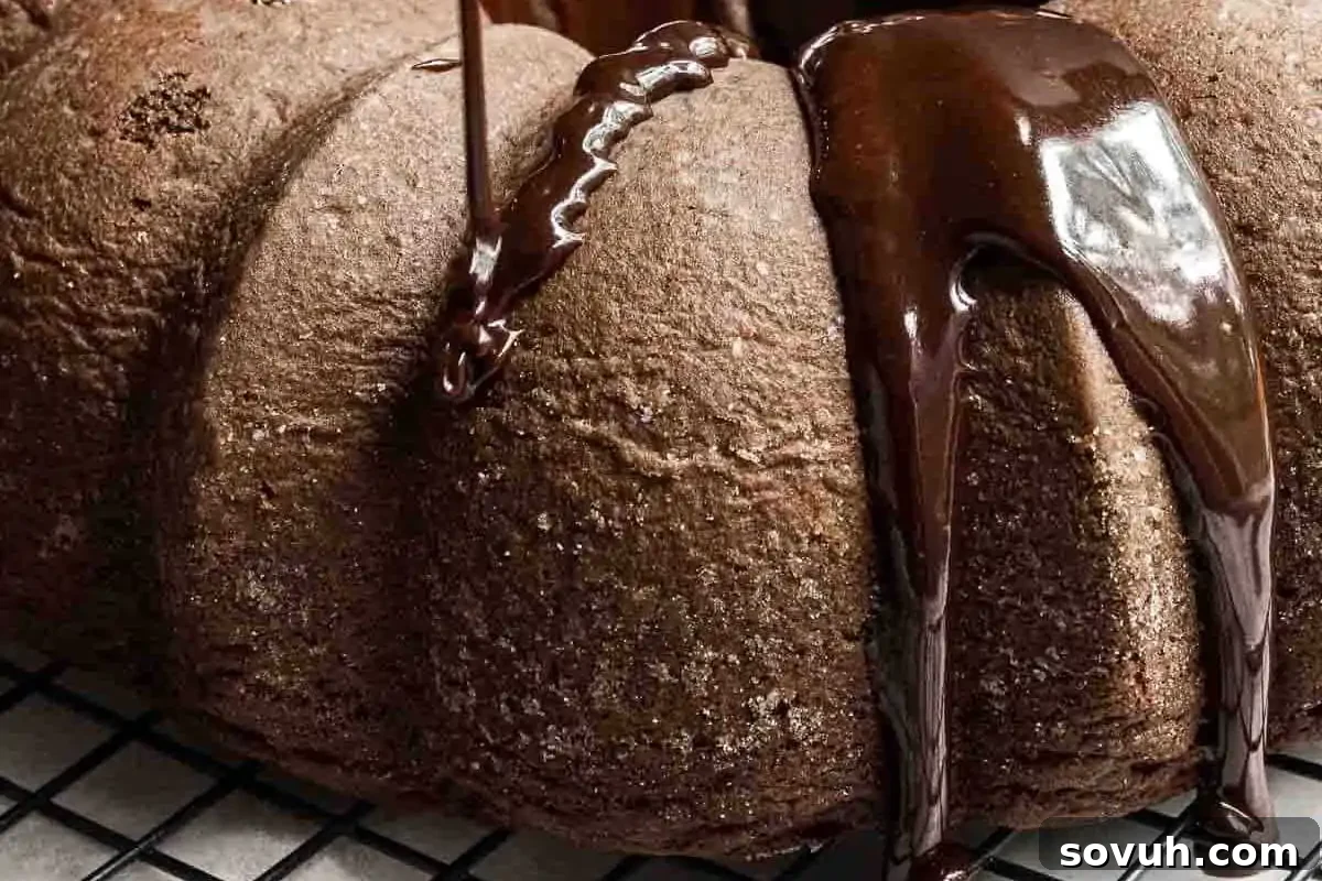 A close-up of a chocolate bundt cake on a cooling rack, with chocolate glaze being poured over the top—proving that simple recipes can look and taste like a Piece of Cake.