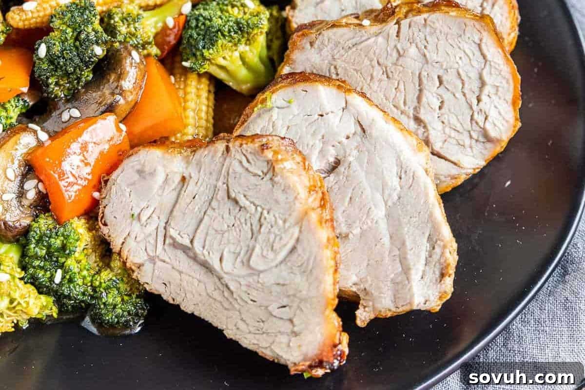 Sliced cooked pork served on a black plate with broccoli, mushrooms, baby corn, and red bell peppers, garnished with sesame seeds.
