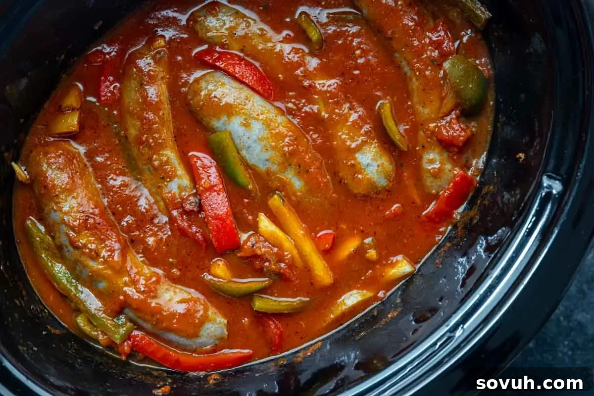 Sausages simmering in tomato sauce with sliced red and green bell peppers in a slow cooker make this classic Italian sausage and peppers slow cooker dish extra flavorful.