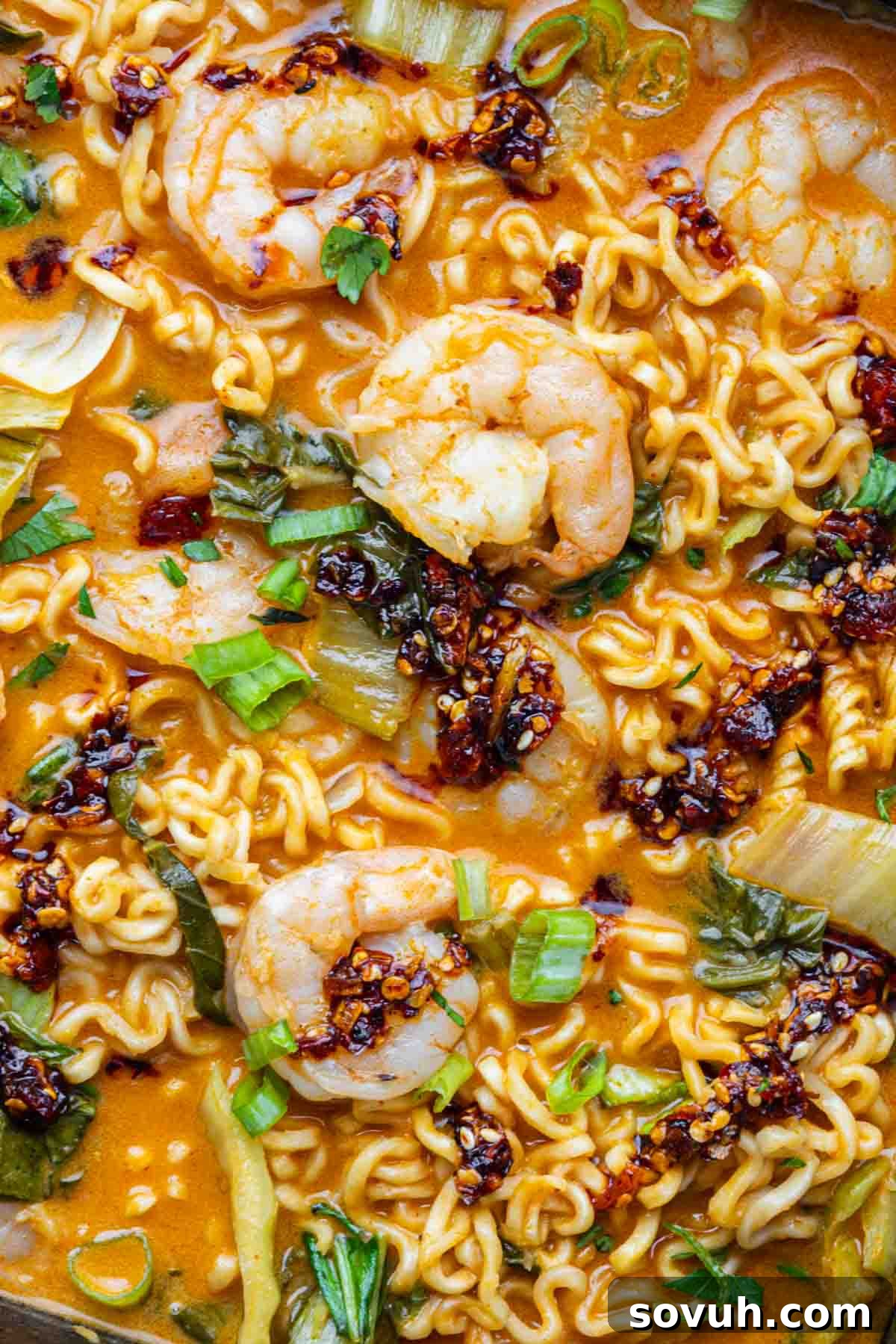 Close-up of Shrimp Ramen Bake with noodles, bok choy, green onions, and chili oil in a spicy broth—an easy ramen casserole perfect for quick weeknight meals.