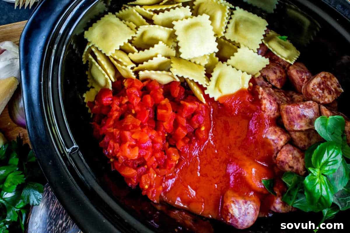 A slow cooker filled with uncooked ravioli, chopped tomatoes, rich tomato sauce, flavorful meatballs, and garnished with fresh basil leaves, ready for a hearty fall casserole.