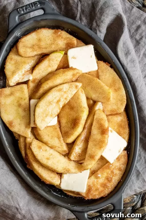 Prepared raw apple slices coated in cinnamon sugar, ready for baking