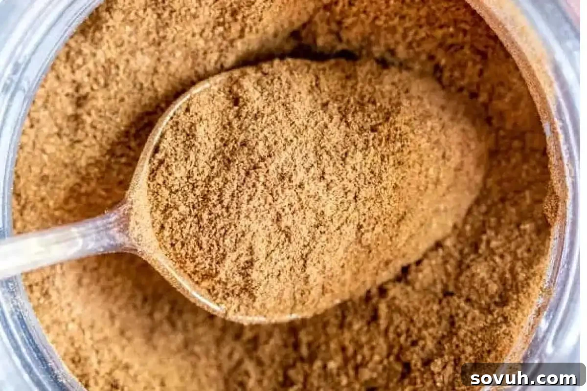 A close-up of ground cinnamon in a spoon inside a jar.