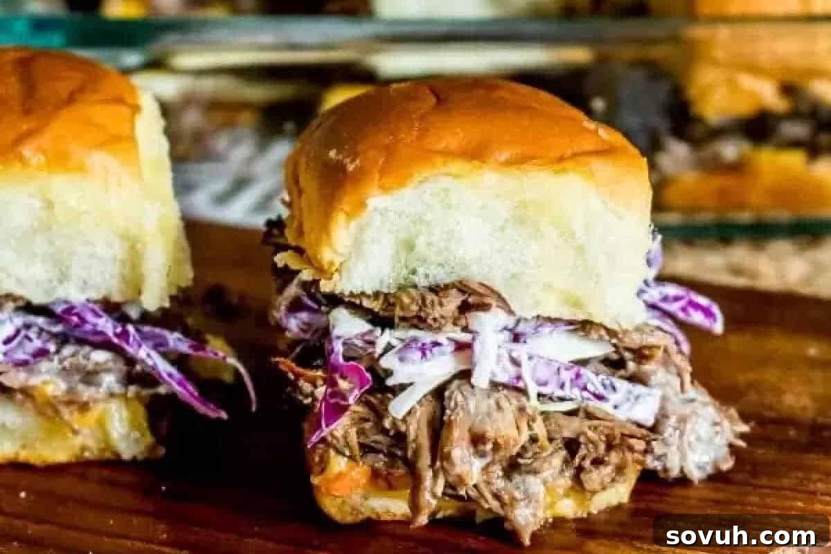 Close-up of a pulled pork slider topped with coleslaw, placed on a wooden surface.