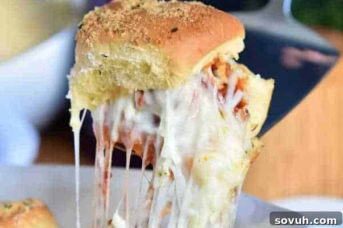 A close-up of a cheese-filled bread roll being lifted, showing melted, stretchy cheese and a golden-brown top.