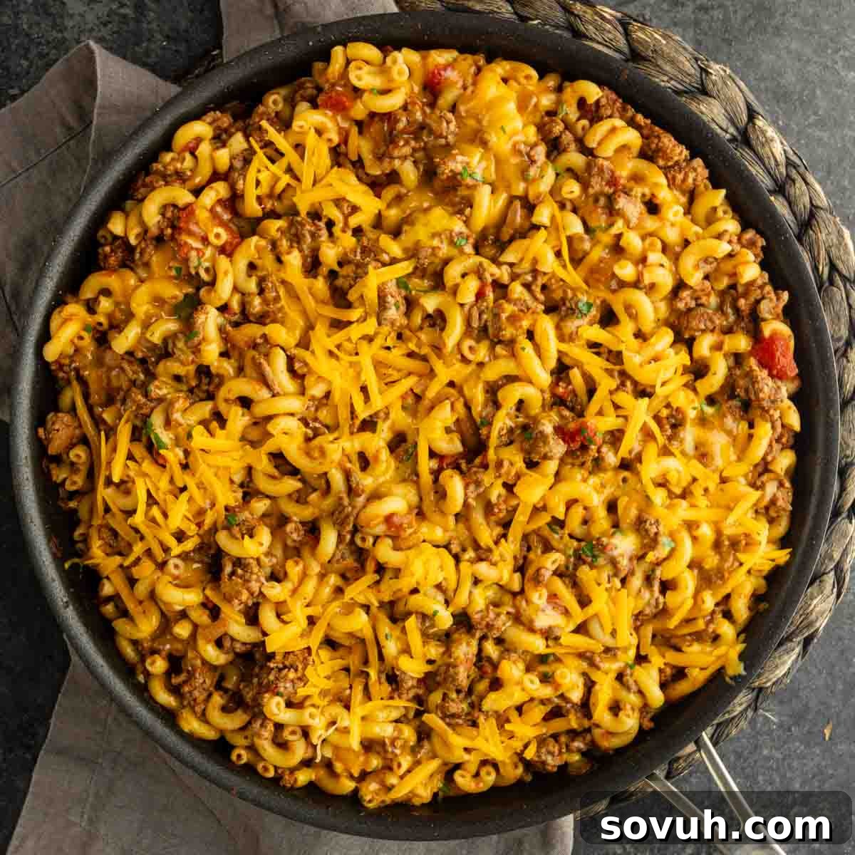 A skillet filled with macaroni pasta mixed with ground beef, tomatoes, and topped with shredded cheddar cheese—this classic skillet goulash is the perfect old fashioned goulash for a comforting meal.