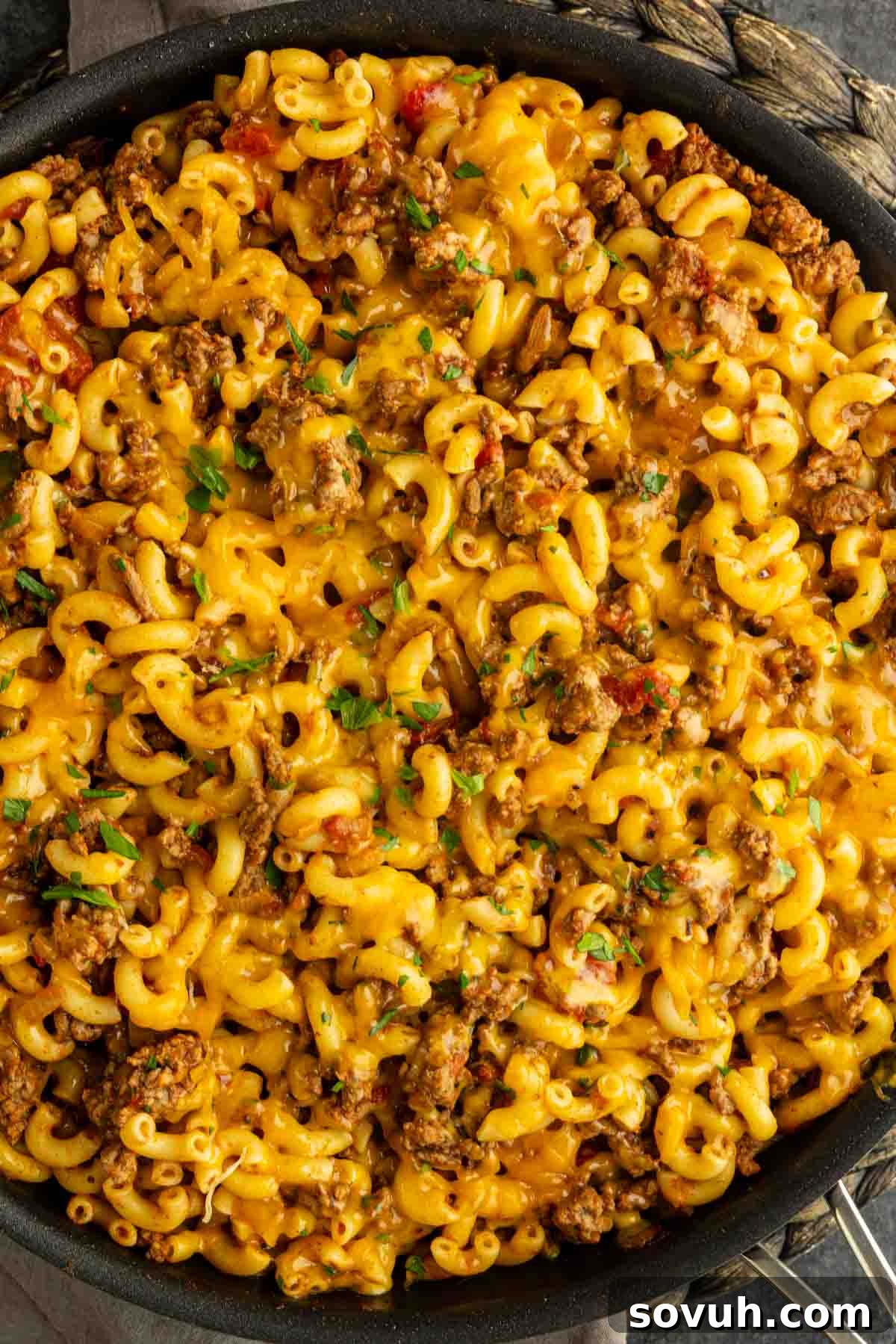 A skillet filled with cooked macaroni, ground beef, cheese, and herbs, resembling a classic American goulash—an easy ground beef pasta recipe perfect for a cozy homemade casserole.