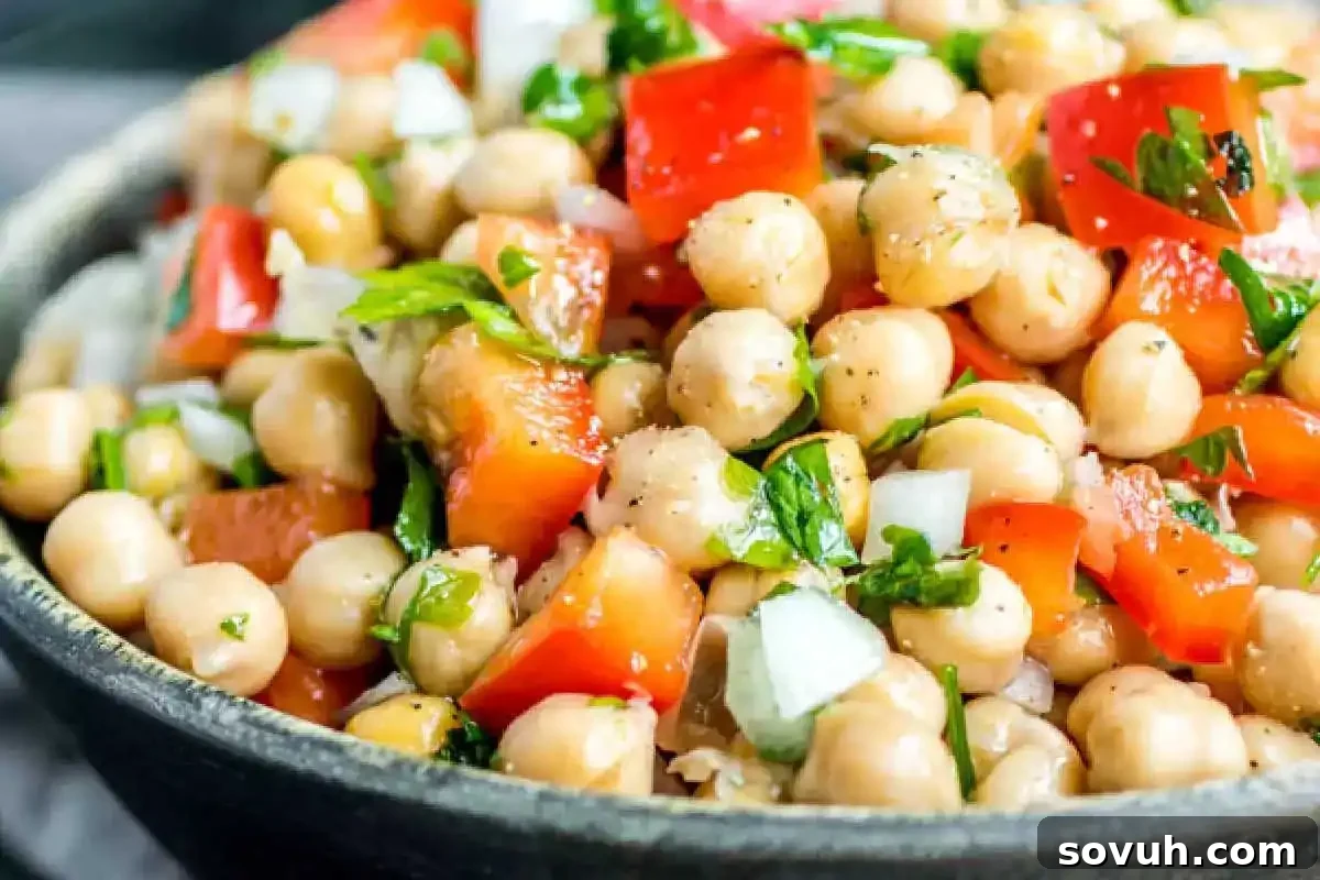 A vibrant bowl of Salada de Grão de Bico, a refreshing Portuguese chickpea salad with chopped tomatoes, bell peppers, onions, and parsley.