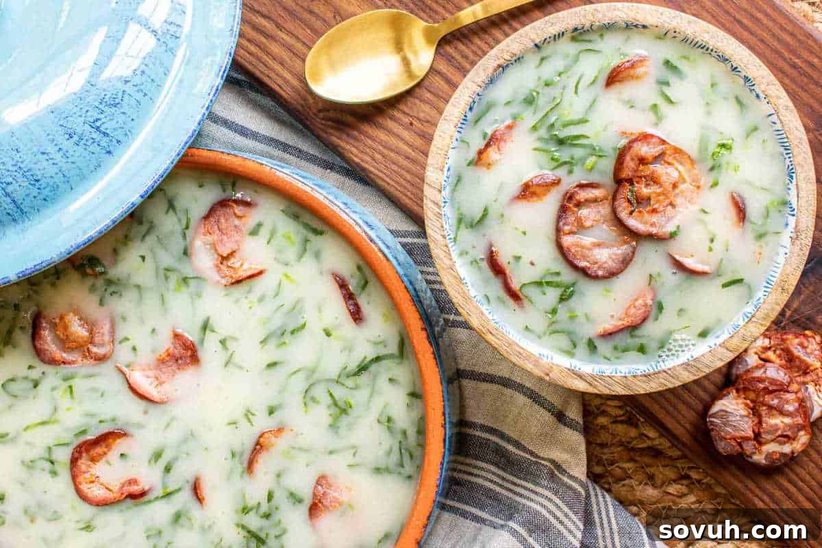A comforting bowl of traditional Portuguese Caldo Verde, a creamy kale soup garnished with sliced chouriço, served with a golden spoon.