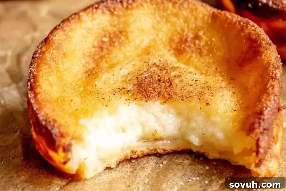 A partially eaten traditional Portuguese Milk Tart (Queijadas de Leite) with a golden-brown crust, creamy filling, and a sprinkle of cinnamon.