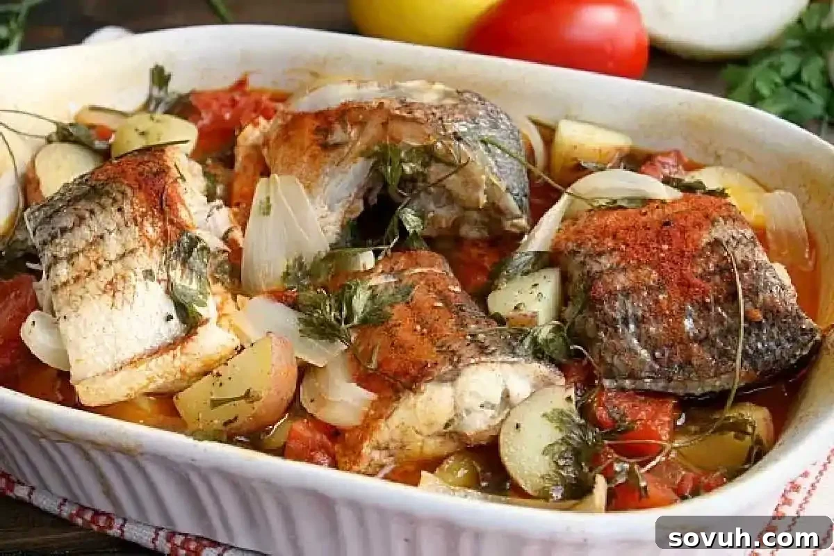 Flavorful Portuguese-style baked rockfish fillets with roasted potatoes, onions, and tomatoes, garnished with fresh herbs in a white ceramic dish.