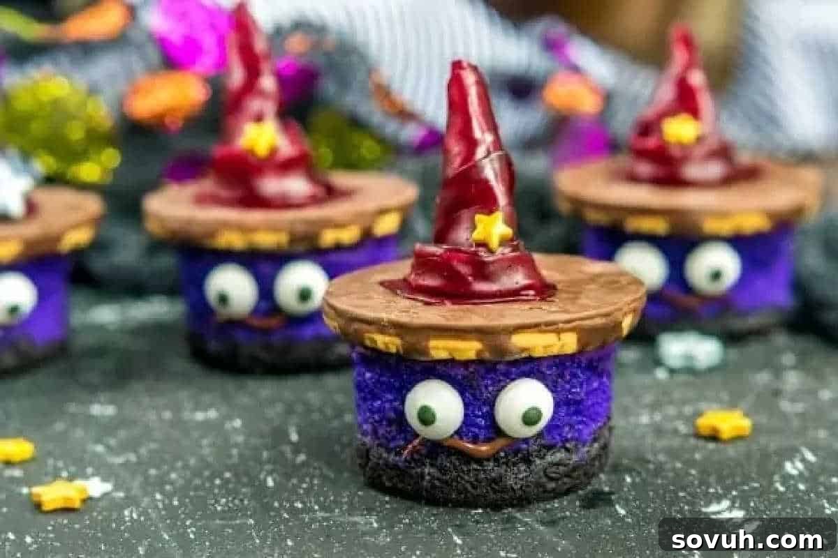 Purple Halloween cupcakes decorated as witches with chocolate hats, star sprinkles, and candy eyes on a dark surface.
