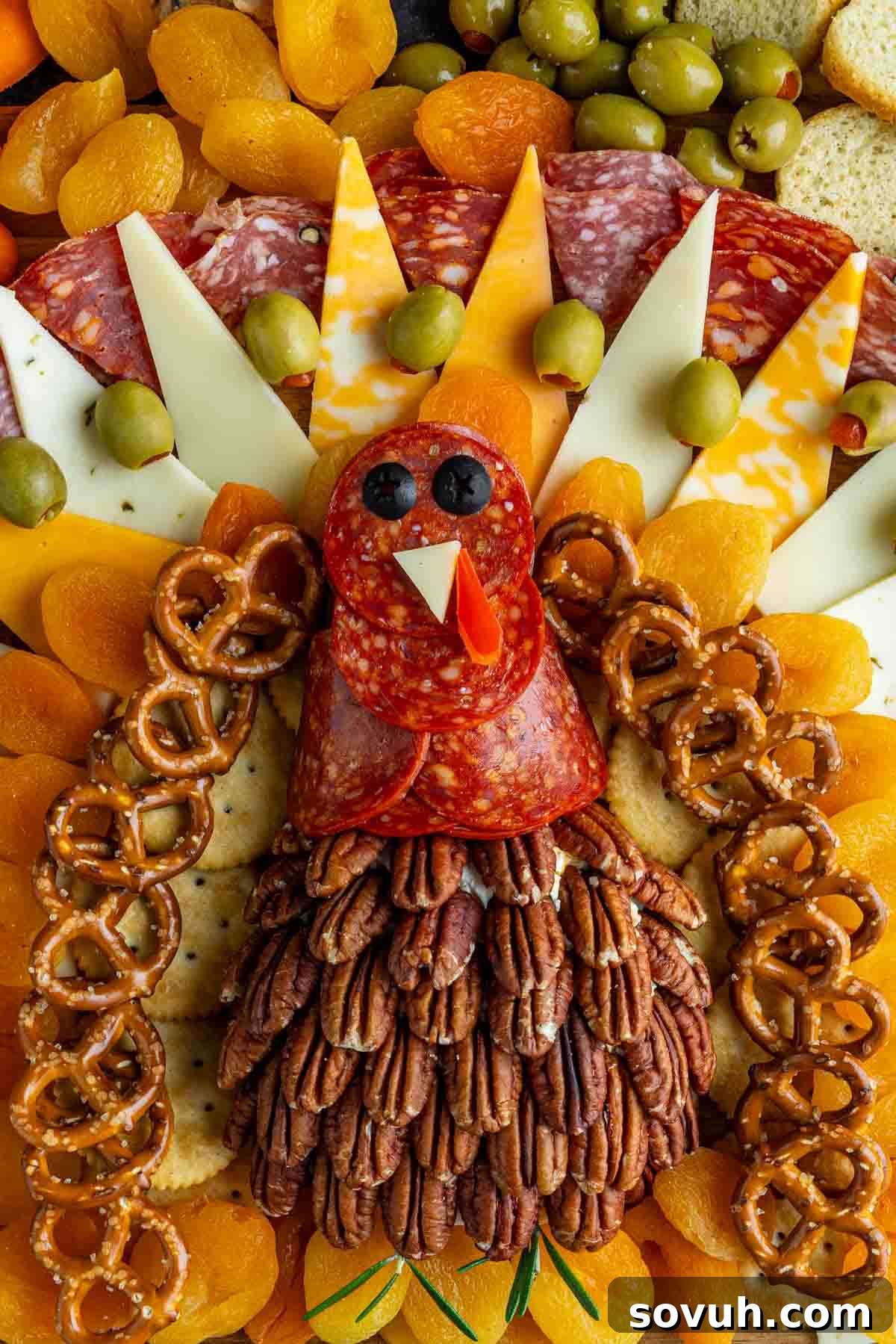 A festive Thanksgiving charcuterie board arranged to resemble a turkey, featuring salami, cheese, olives, dried apricots, pretzels, and pecans artfully forming the bird’s body, feathers, and face—a perfect holiday charcuterie board centerpiece.