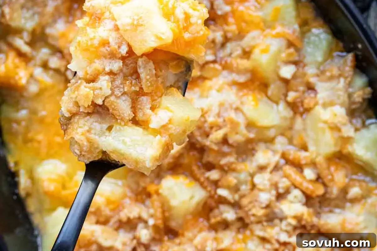 A bowl of pineapple casserole with a spoon in it.