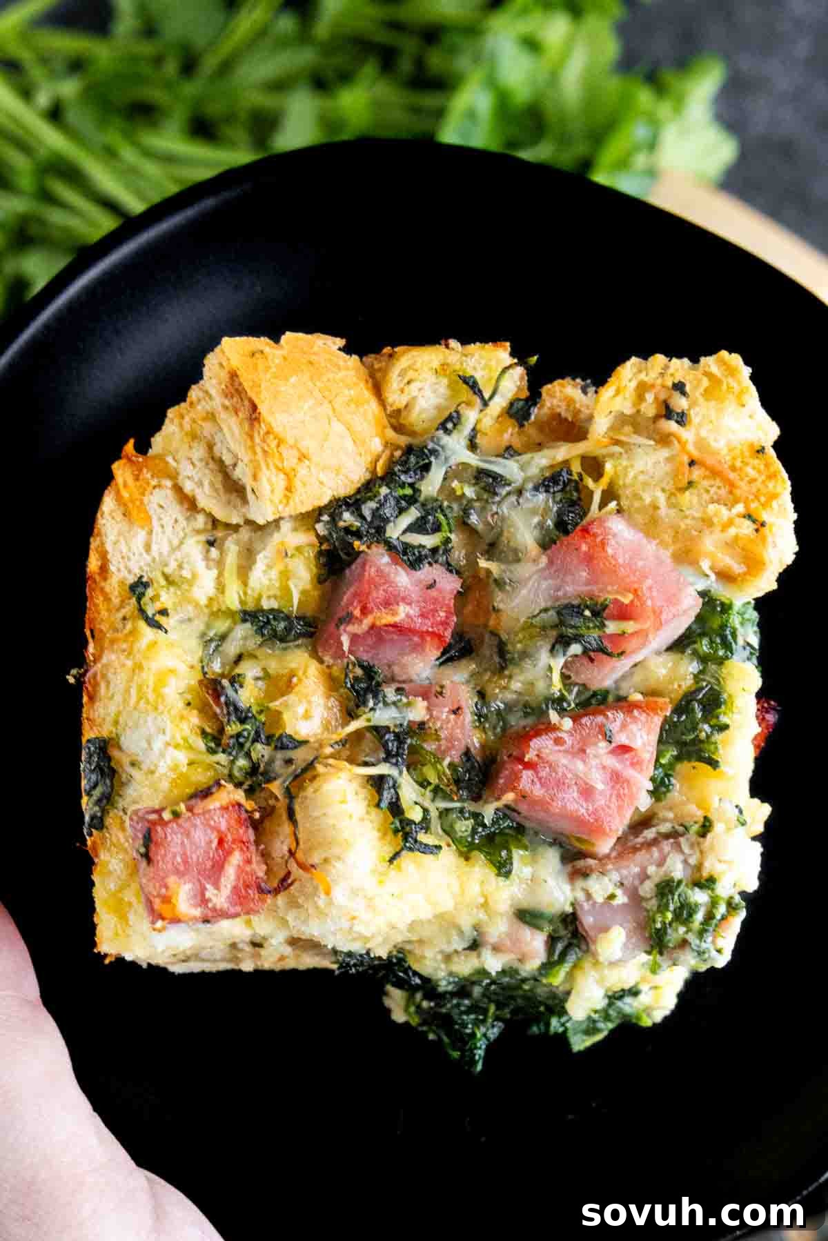 A slice of Ham and Cheese Strata on a black plate.