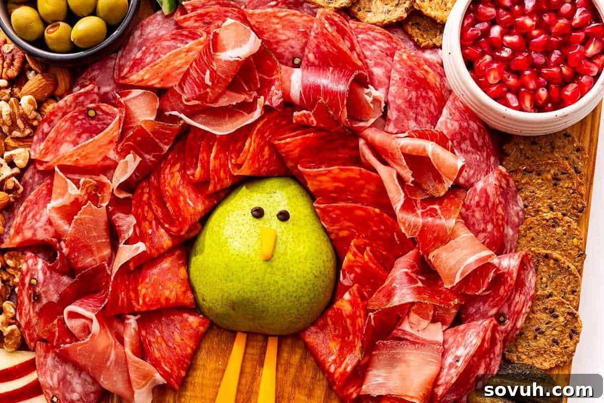 A charming Turkey Charcuterie Board arranged like a festive turkey, featuring a pear body, savory cured meats as feathers, and a vibrant display of olives, pomegranate seeds, nuts, and crackers.