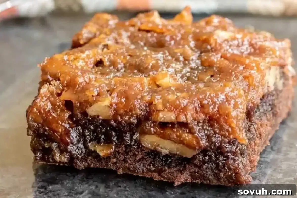 A close-up of a single slice of gooey chocolate and nut dessert bar on a dark surface.