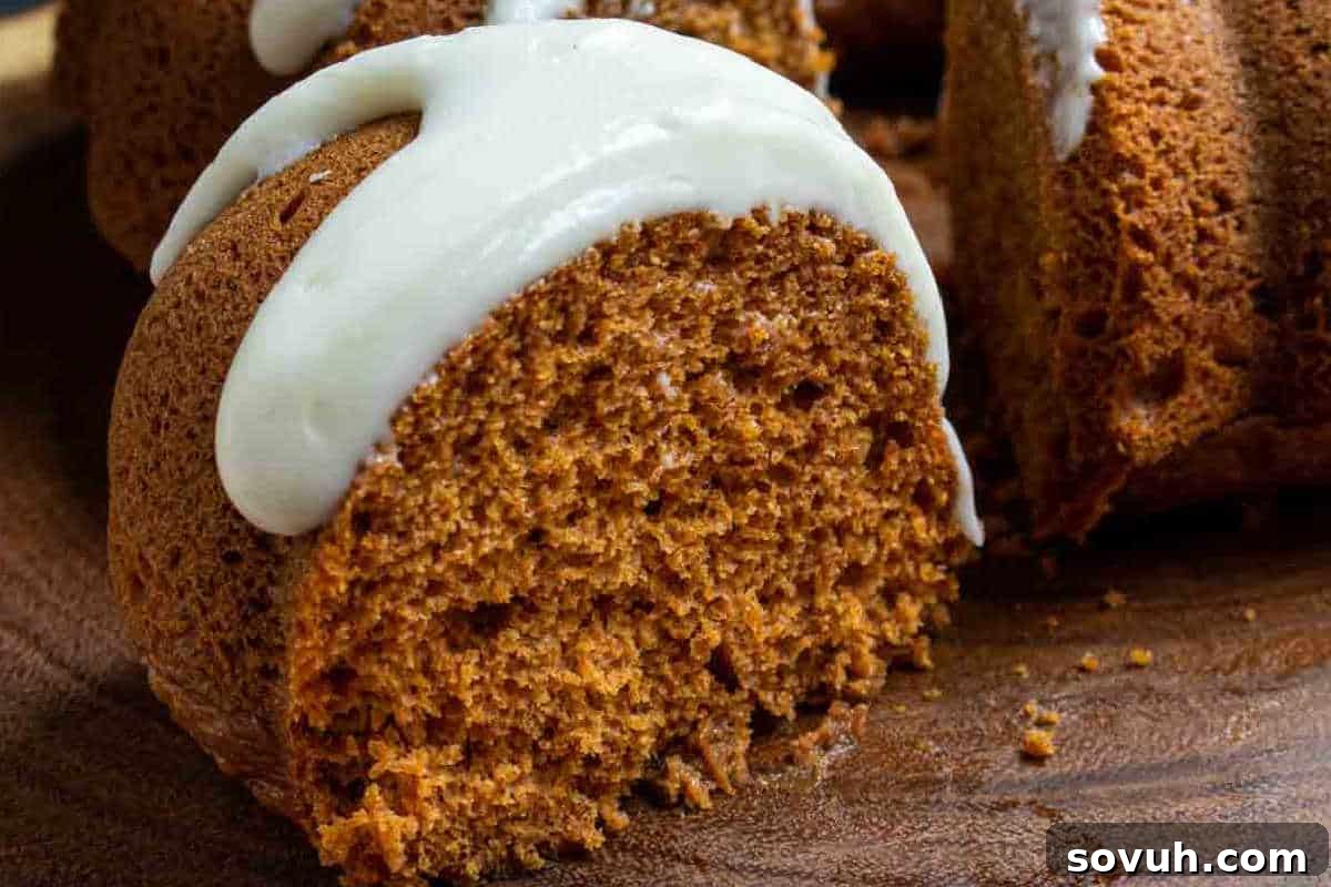 A sliced bundt cake with a light brown interior and white icing drizzled on top.
