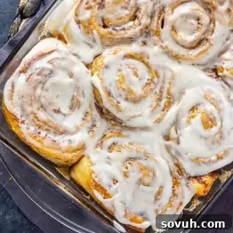 A glass baking dish filled with TikTok cinnamon rolls covered in white icing, viewed from above—a viral and easy cinnamon roll hack using heavy cream for extra softness.