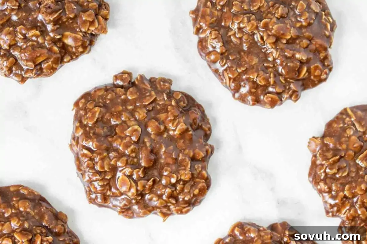 Several Santa Approved no-bake chocolate oatmeal cookies are arranged on a white marble surface, making perfect Christmas Cookies for the holiday season, highlighting their quick preparation.