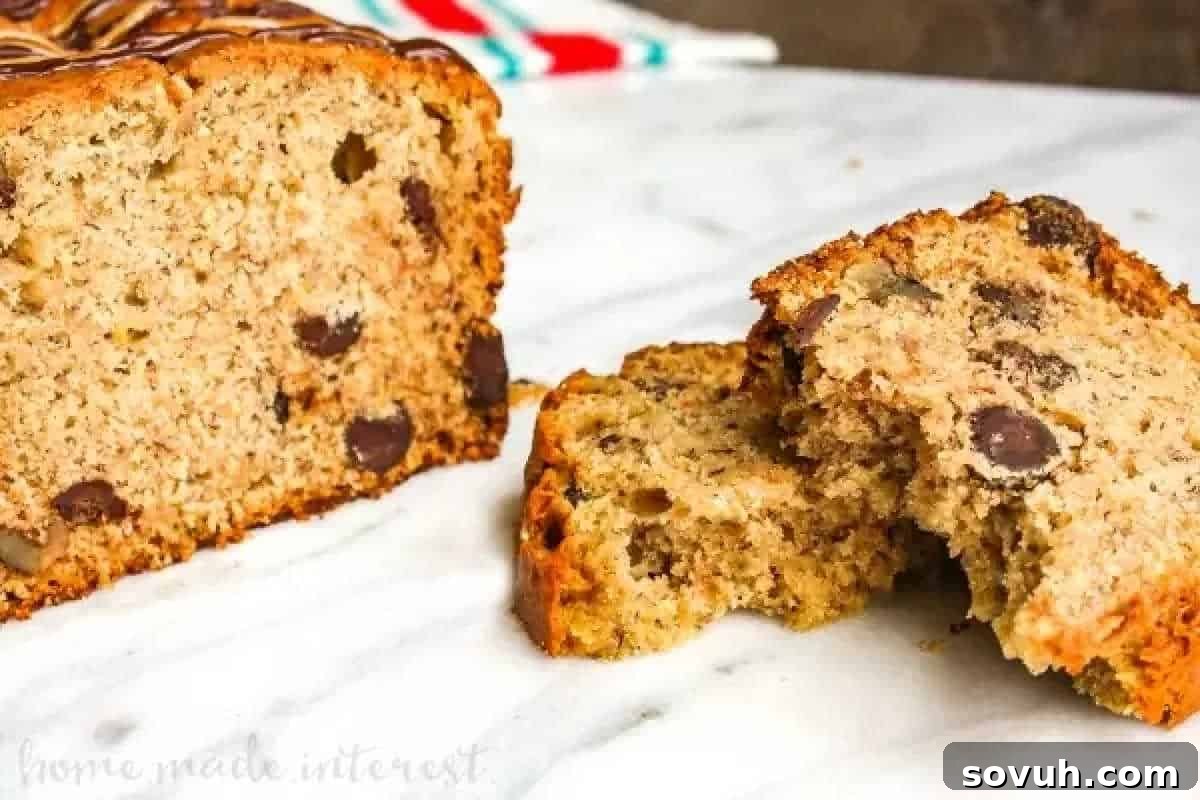 Sliced banana bread with chocolate chips and nuts on a marble surface.