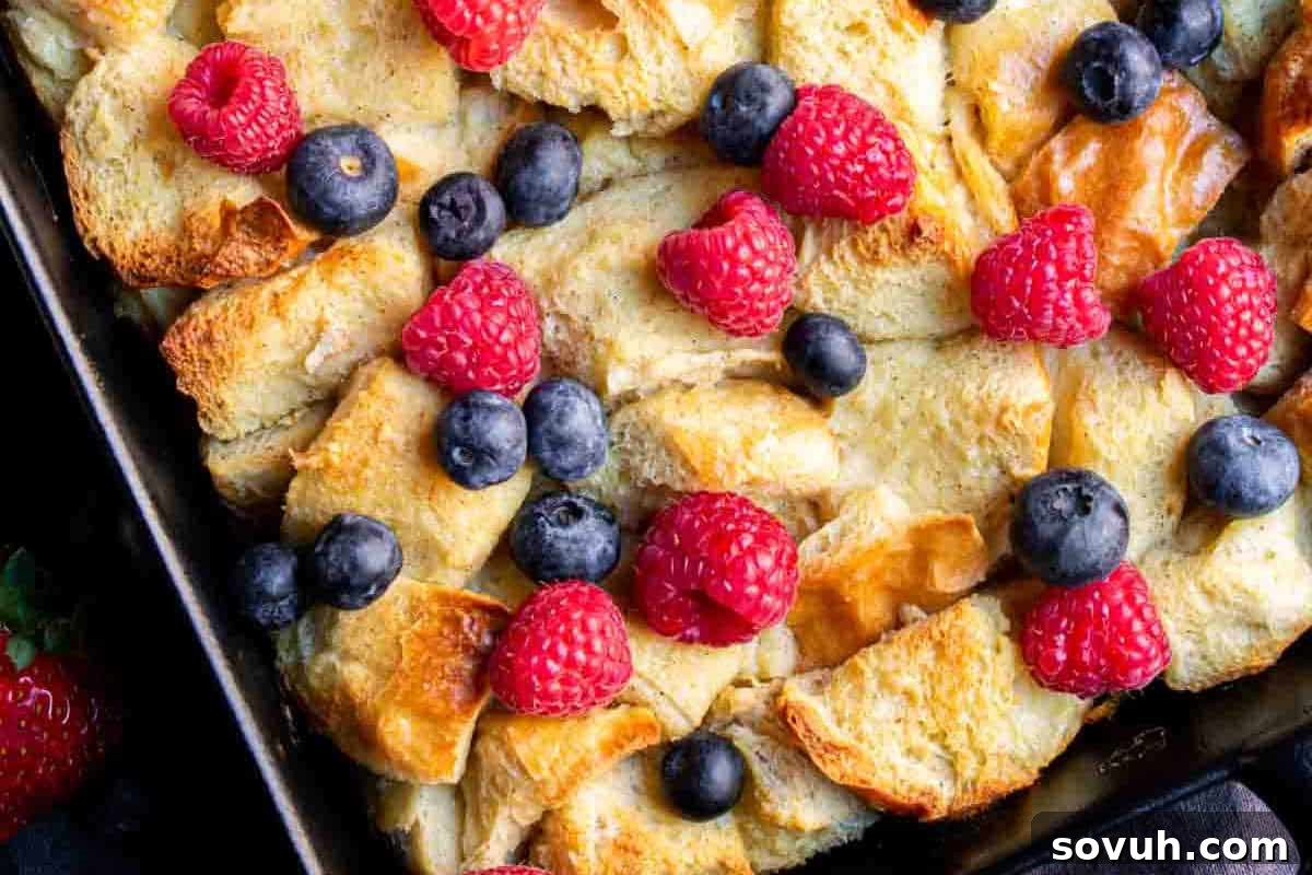 Close-up of a baked bread pudding topped with raspberries and blueberries.