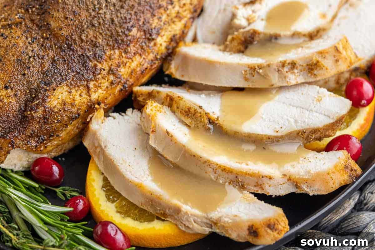Slices of perfectly roasted turkey, drenched in savory gravy, artfully arranged on a black plate, adorned with bright orange slices, crimson cranberries, and fragrant rosemary.