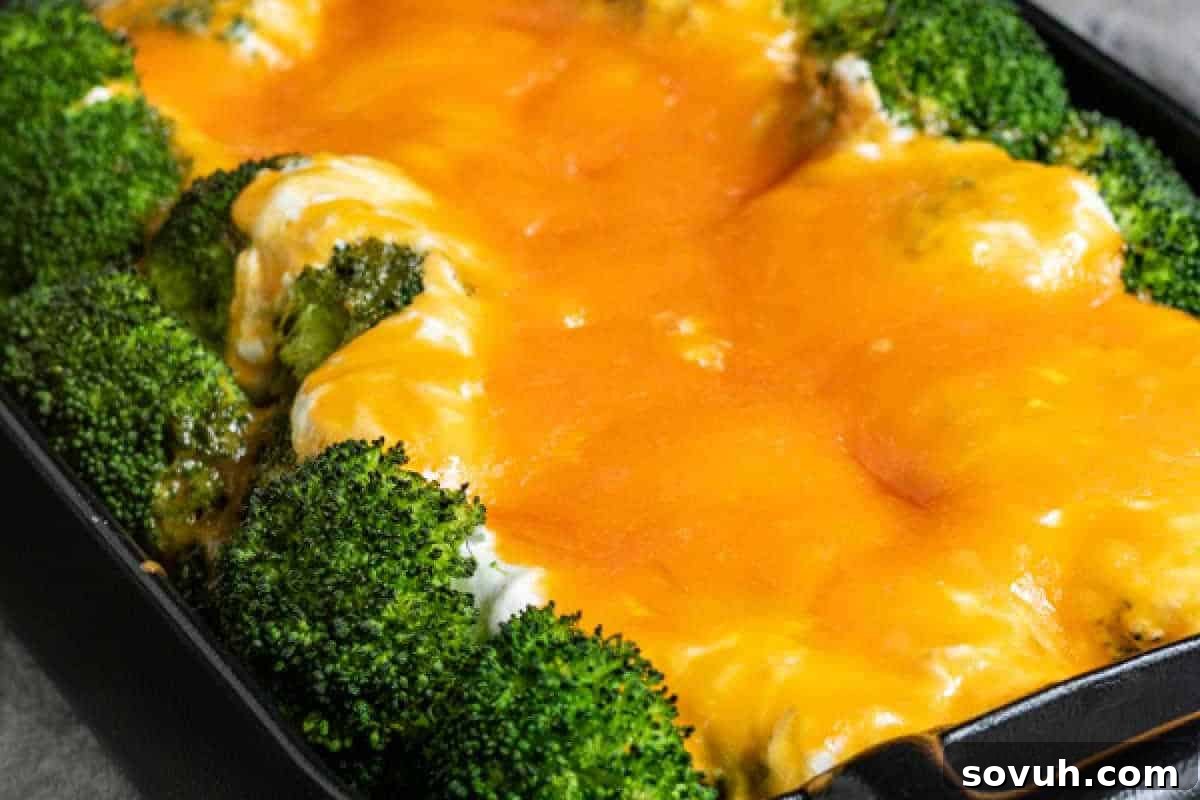 Baked broccoli casserole topped with melted cheddar cheese in a black dish.