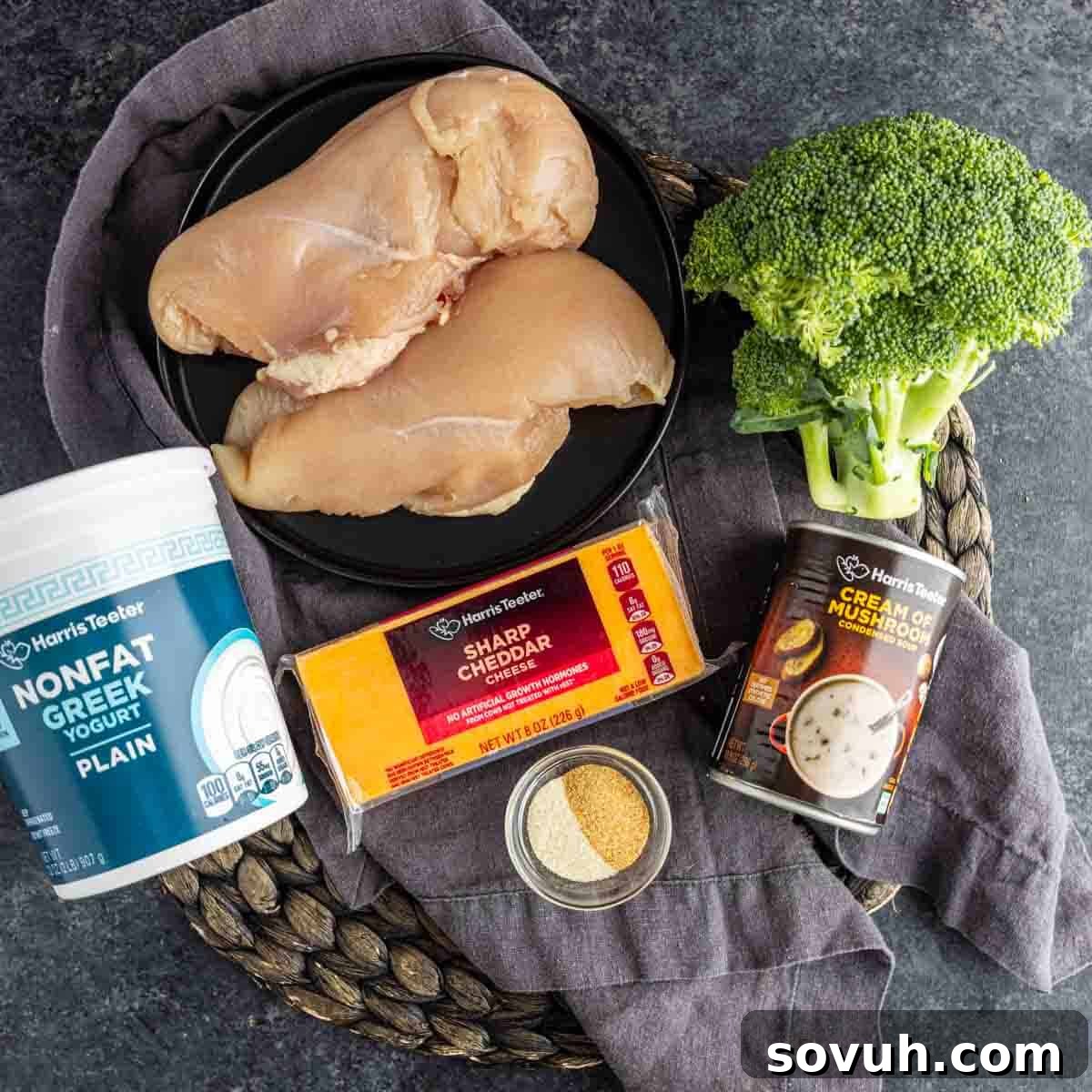 Raw chicken breasts on a plate, broccoli, a can of cream of mushroom soup, nonfat Greek yogurt, sharp cheddar cheese, and a bowl of seasoning—perfect for an easy high protein lunch or low calorie chicken broccoli casserole.