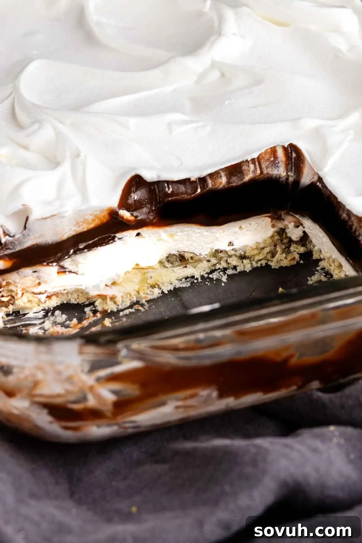 Decadent Chocolate Dream 5 A glass baking dish with a layered chocolate lasagna dessert featuring a whipped topping, rich chocolate layer, and crumbly crust, with a section missing to show the delicious layers.