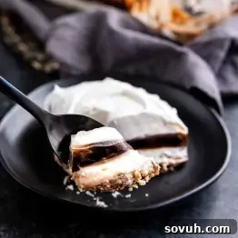 Decadent Chocolate Dream 7 A fork holds a bite of layered chocolate dessert with whipped topping, resting on a black plate.