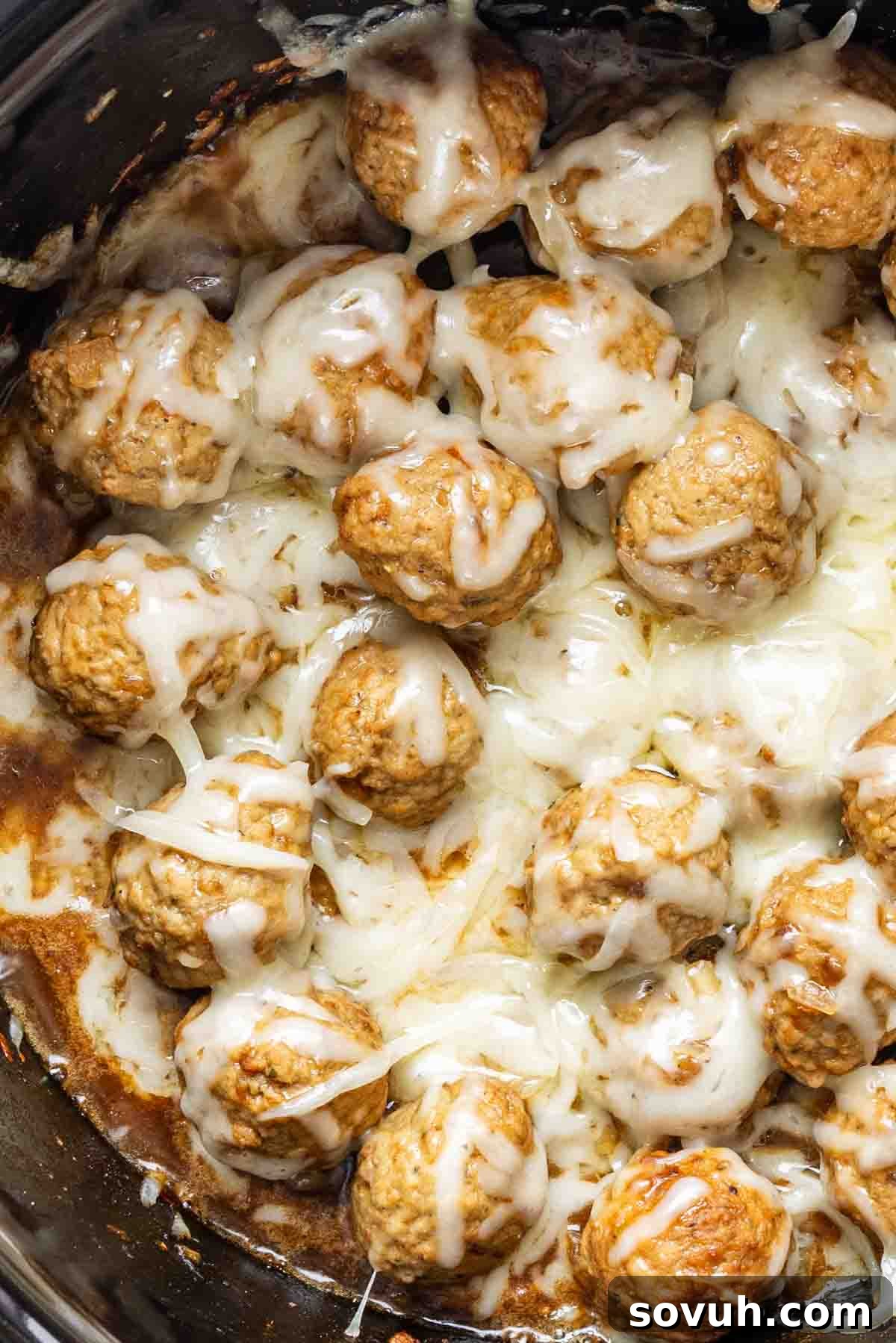 Frozen meatballs slow cooker style: cooked meatballs smothered in melted cheese, savory sauce, and a hint of French onion soup mix for an easy appetizer meatballs recipe.