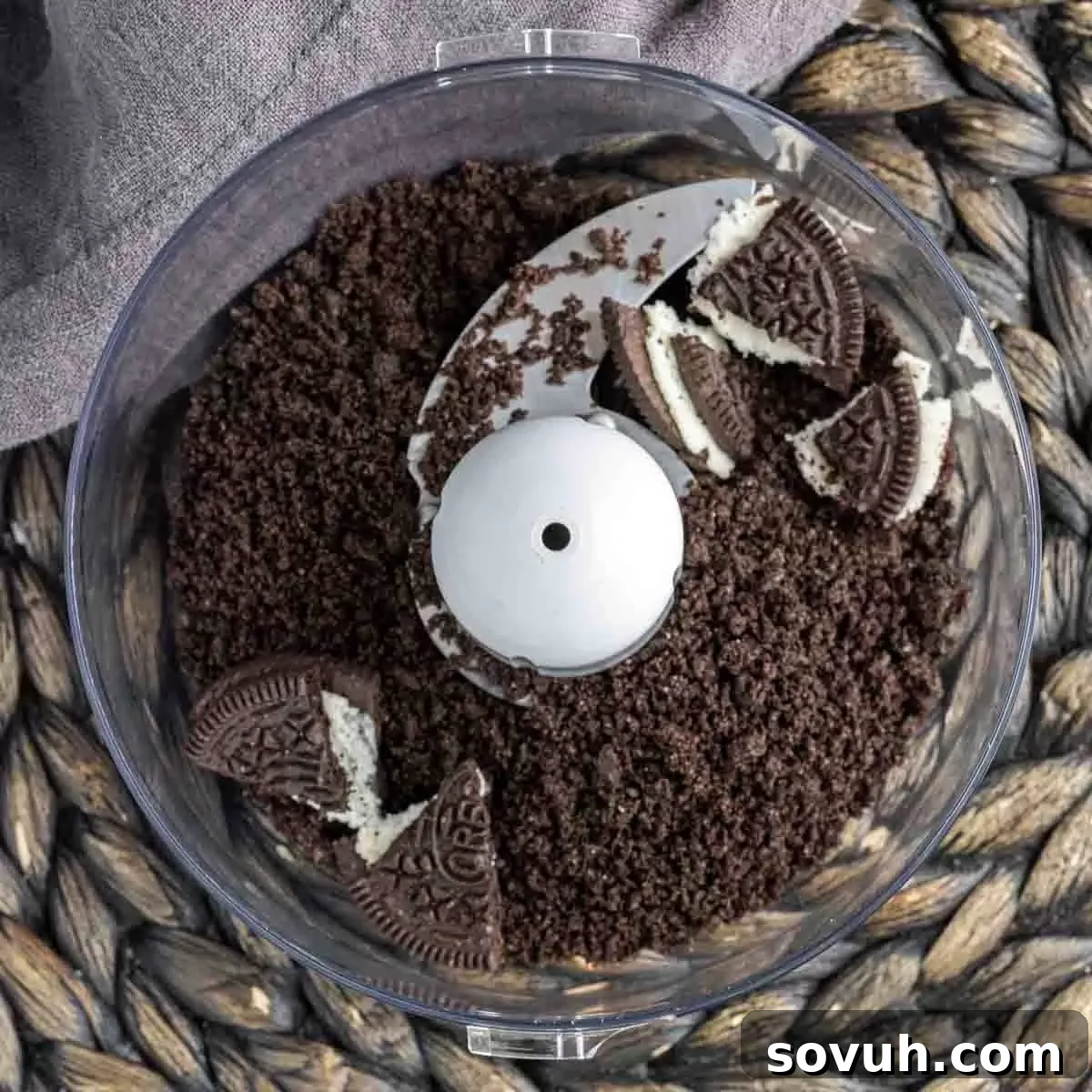Oreo cookies being crushed in a food processor, a key step for the crust and topping of Oreo Magic Bars.