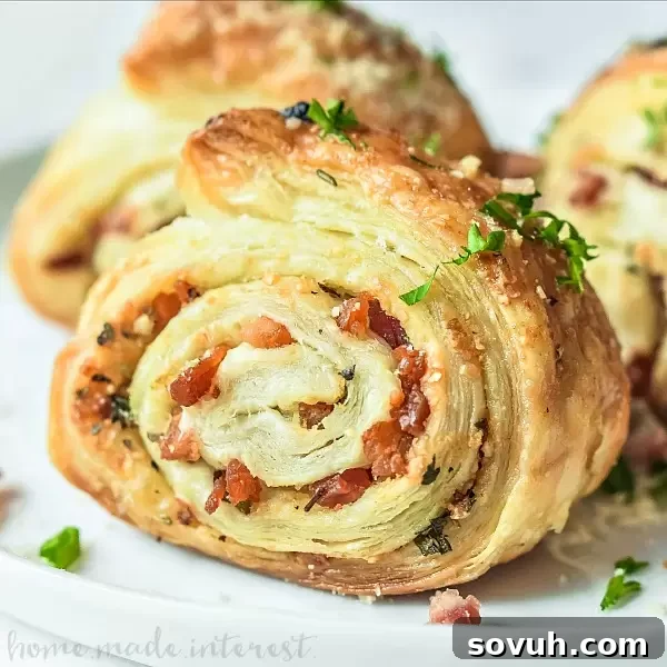 Parmesan Puff Pastry Pinwheel on a black plate with fresh herbs