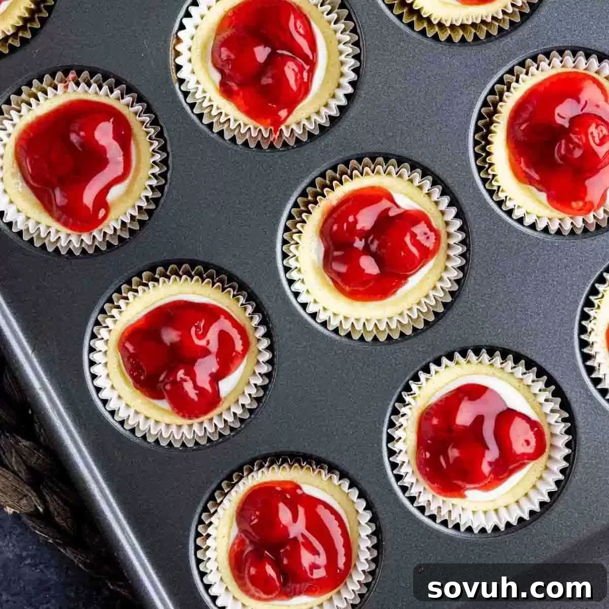 Honey pecan cheesecake cupcakes baked in a muffin tin, topped with fruit