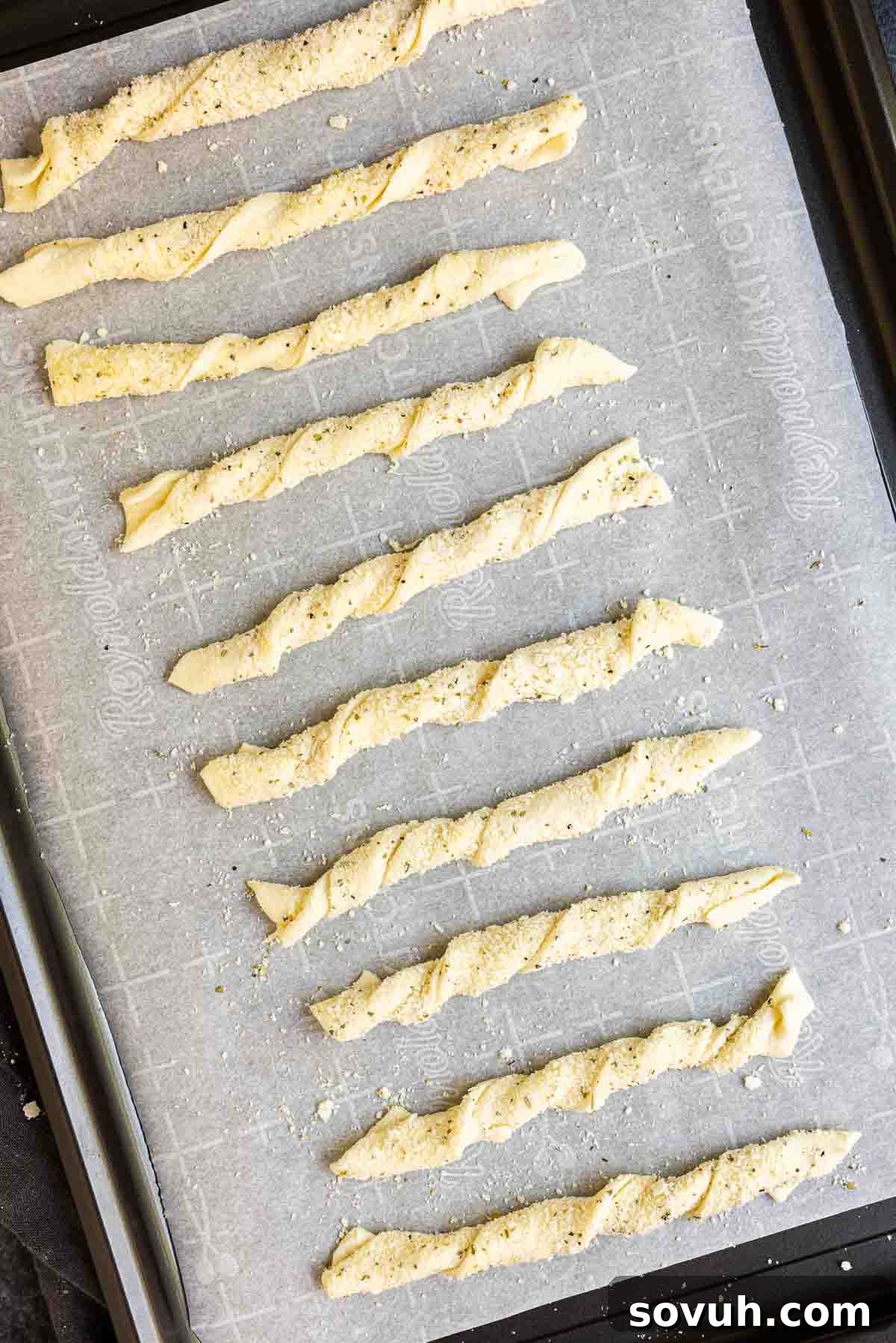 Individual puff pastry strips being twisted into their signature cheese twist shape.