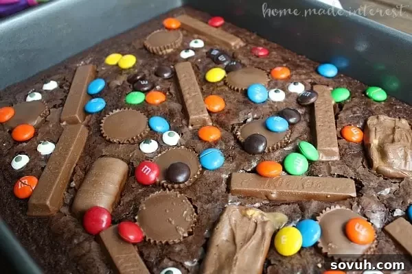 A tray of ooey, gooey, chocolate Witch's Brew Brownies packed with various Halloween candies, ready for a party.
